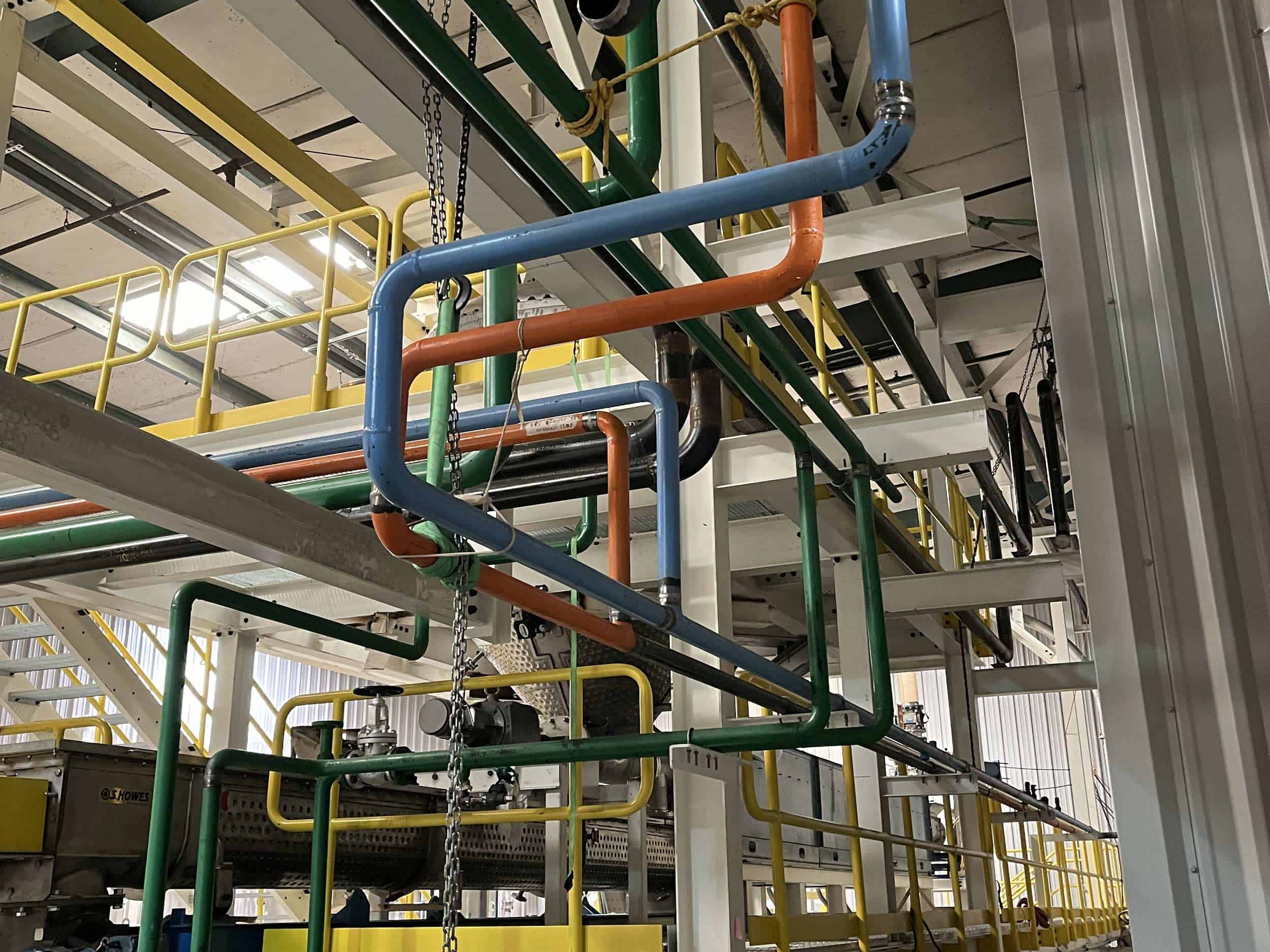 Industrial pipes in a factory setting with walkways.